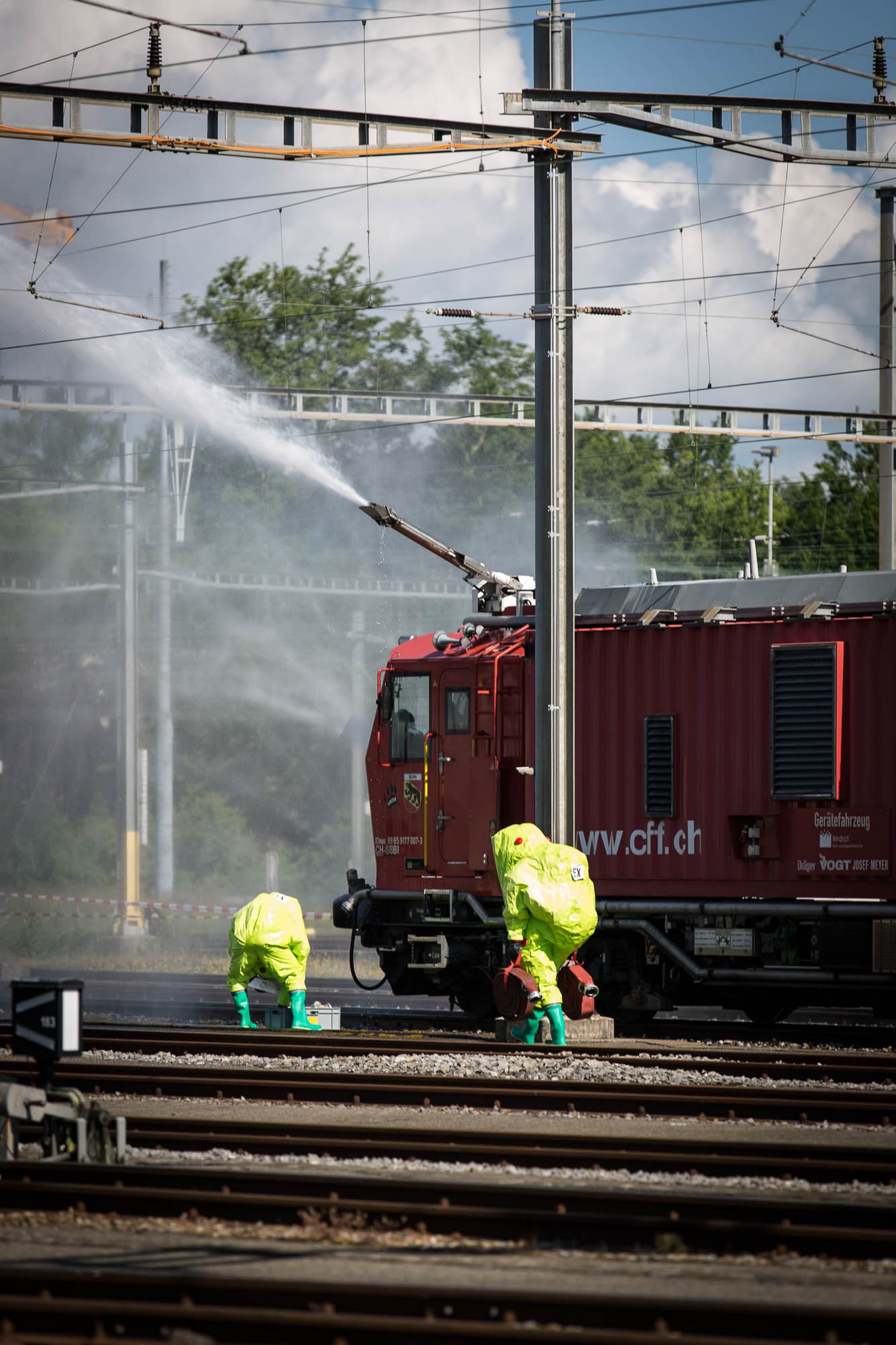 Photo illustrant des pompiers munis de tenue lourde étanche et rideau d’eau déployé par le train d’extinction et de secours des CFF (TES)
