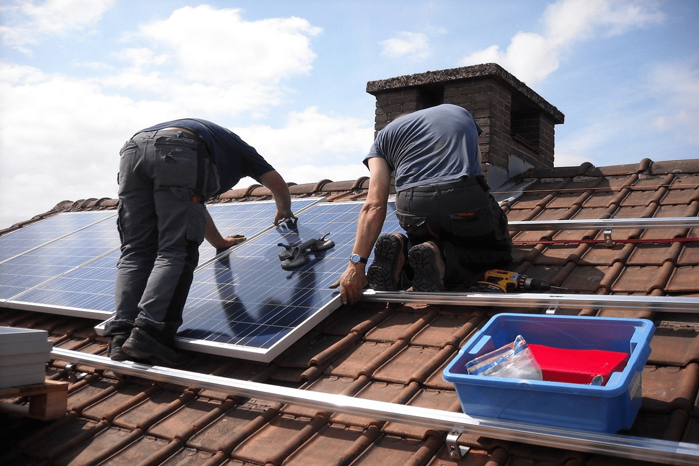 Photo d'illustration de deux personnes installant des panneaux solaires sur un toit